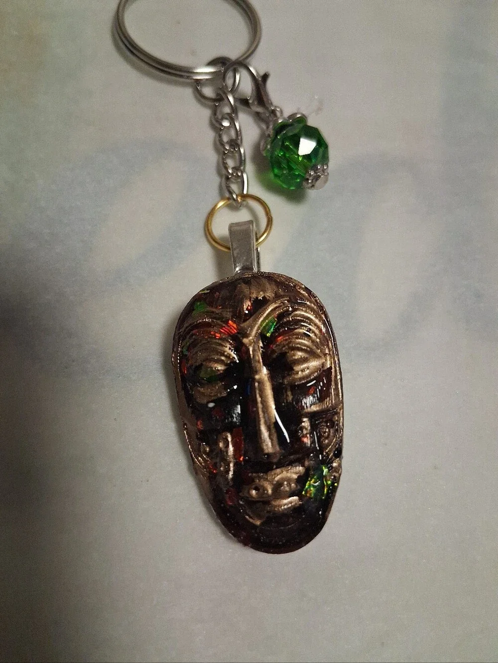 Artisan Bronze Mask Keychain with Green Crystal Accent